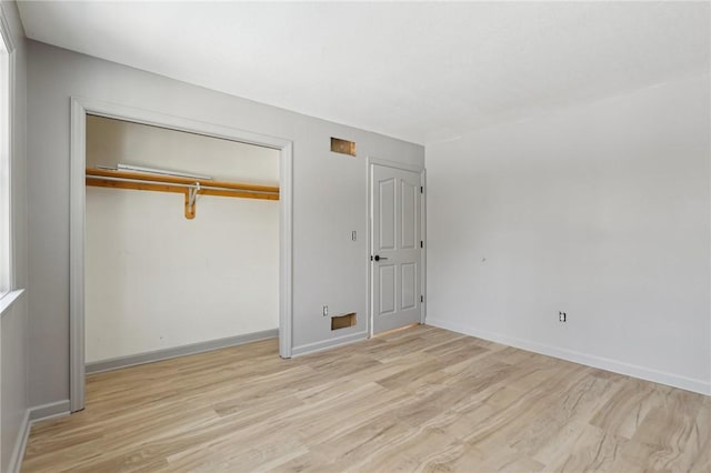 unfurnished bedroom with baseboards, wood finished floors, and a closet