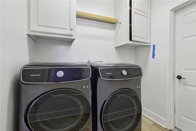 laundry area featuring cabinet space, wood finished floors, baseboards, and separate washer and dryer