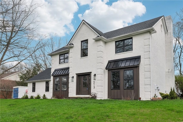 view of front of property featuring a standing seam roof, a front lawn, brick siding, and metal roof