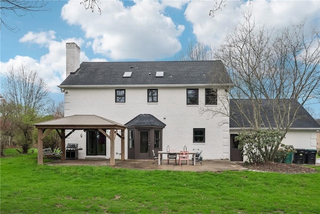 back of property featuring a patio area, a chimney, a gazebo, and a yard
