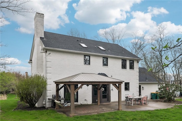 rear view of property featuring a gazebo, a patio area, brick siding, and a chimney