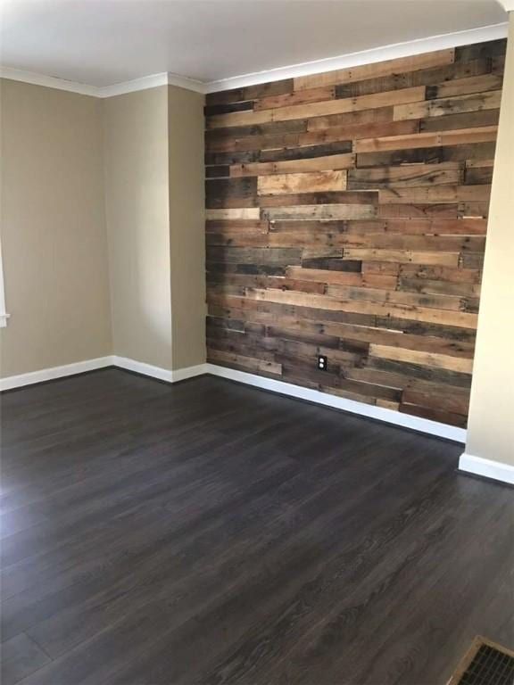 empty room with ornamental molding, dark hardwood / wood-style flooring, and wooden walls