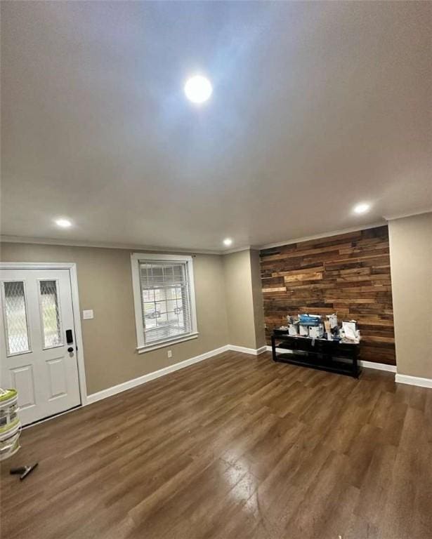 unfurnished living room featuring crown molding, dark wood-type flooring, and wood walls