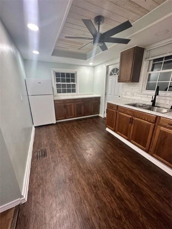 kitchen with sink, ceiling fan, backsplash, dark hardwood / wood-style floors, and white fridge