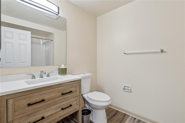 bathroom featuring hardwood / wood-style flooring, vanity, walk in shower, and toilet