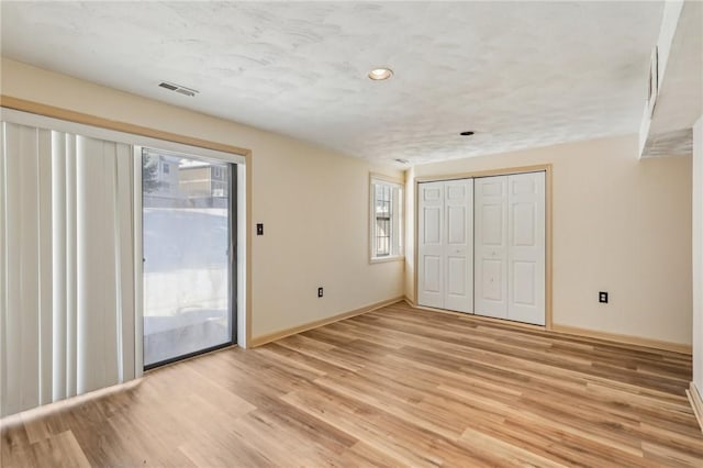 unfurnished bedroom with wood-type flooring, access to exterior, a textured ceiling, and a closet