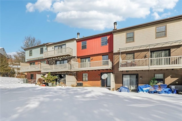 snow covered rear of property featuring central AC unit