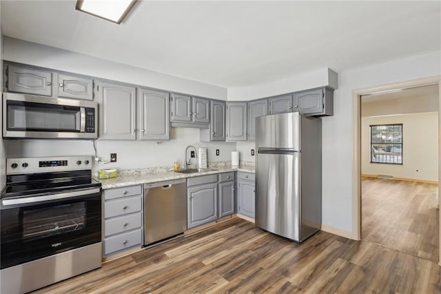 kitchen featuring stainless steel appliances, sink, gray cabinetry, and dark hardwood / wood-style flooring