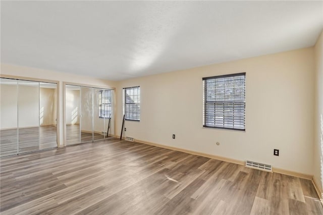 interior space featuring multiple windows, light hardwood / wood-style flooring, and multiple closets