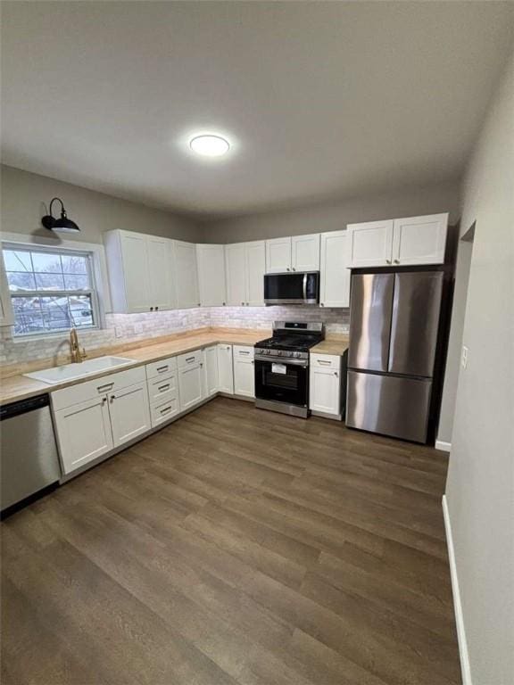 kitchen featuring dark wood-type flooring, sink, tasteful backsplash, stainless steel appliances, and white cabinets