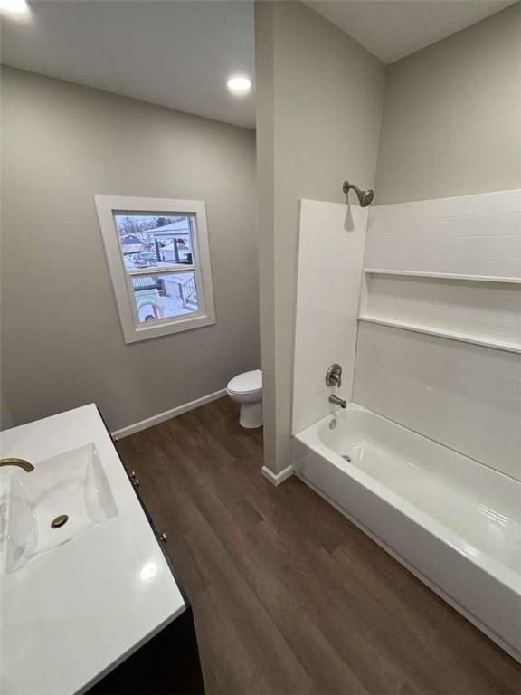 full bathroom featuring hardwood / wood-style flooring, bathing tub / shower combination, vanity, and toilet