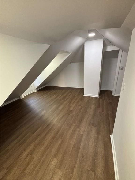 bonus room with dark hardwood / wood-style flooring and vaulted ceiling