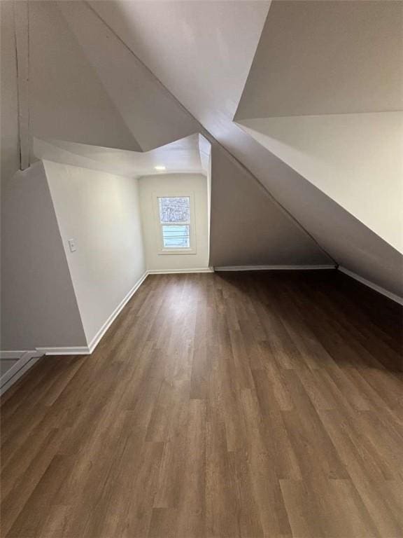 bonus room with dark hardwood / wood-style floors and vaulted ceiling