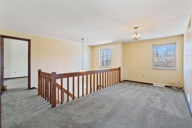 carpeted empty room with a chandelier