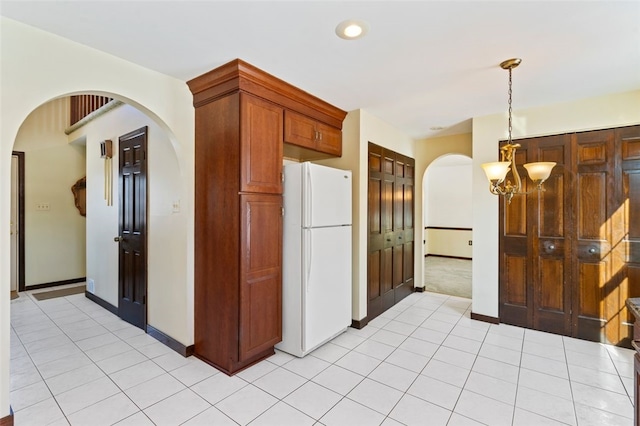 kitchen with hanging light fixtures, white fridge, light tile patterned floors, and a notable chandelier