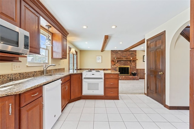 kitchen with sink, light stone counters, white appliances, kitchen peninsula, and light colored carpet