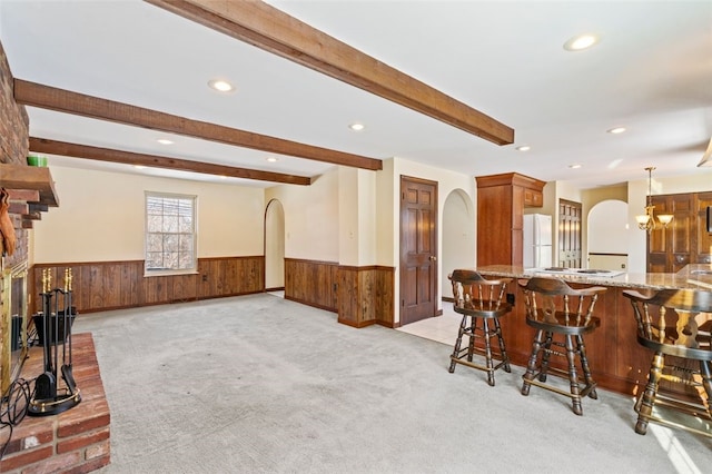 kitchen with beamed ceiling, hanging light fixtures, white fridge, light colored carpet, and kitchen peninsula