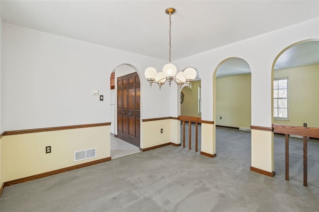 empty room with light carpet and a notable chandelier