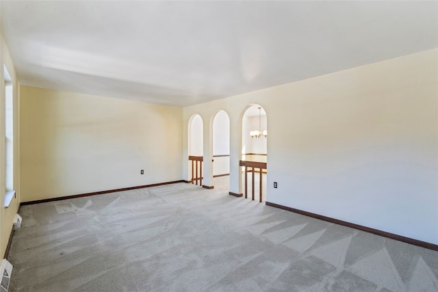 unfurnished room with an inviting chandelier and light colored carpet