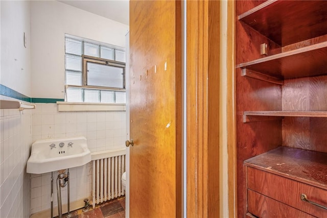 bathroom featuring tile walls, radiator, sink, and toilet