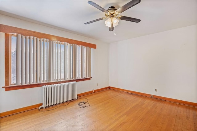 empty room with hardwood / wood-style flooring, ceiling fan, and radiator