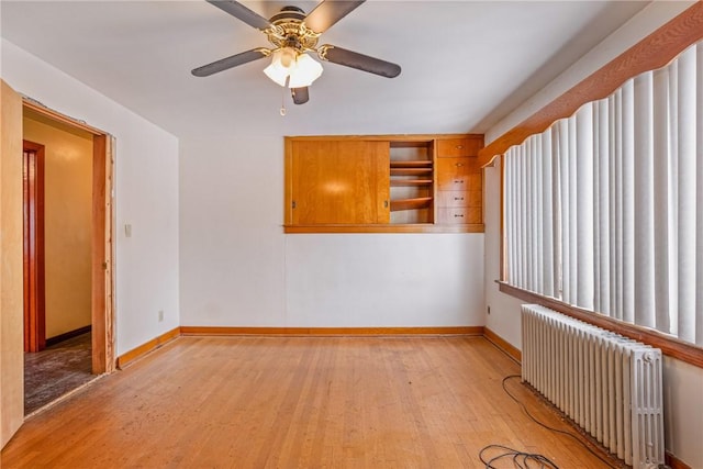 spare room with light hardwood / wood-style flooring, radiator heating unit, and ceiling fan