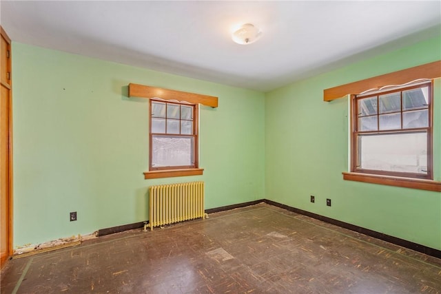 empty room featuring a healthy amount of sunlight and radiator heating unit