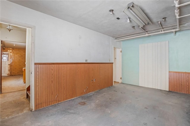 unfurnished room with concrete floors and wood walls