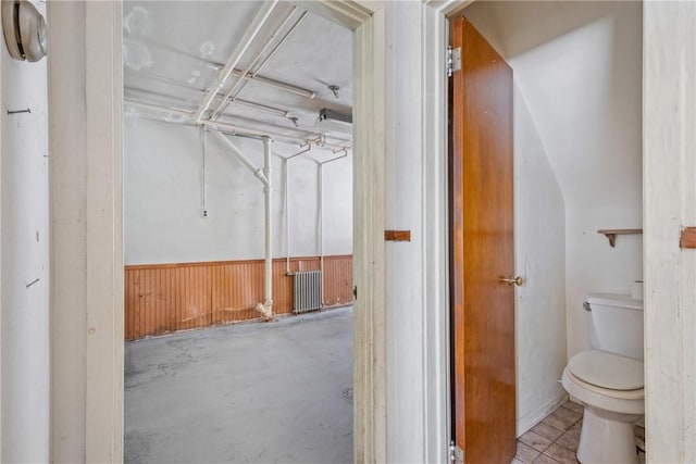 bathroom featuring concrete floors, toilet, and wood walls