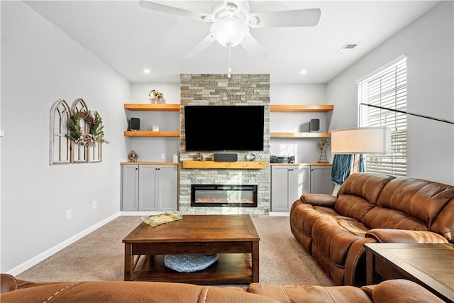 living room featuring a stone fireplace, light colored carpet, and ceiling fan