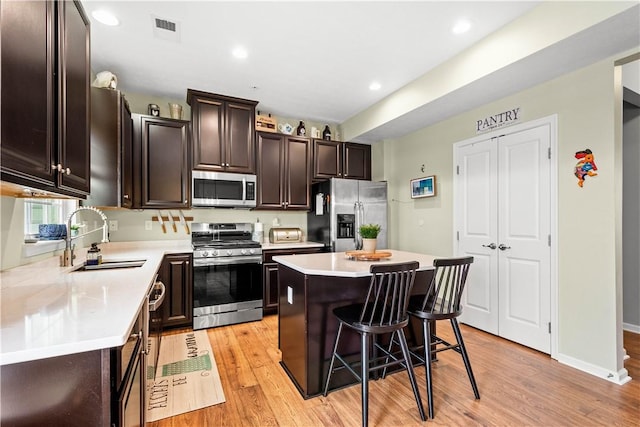 kitchen featuring a kitchen bar, sink, light hardwood / wood-style flooring, appliances with stainless steel finishes, and a kitchen island