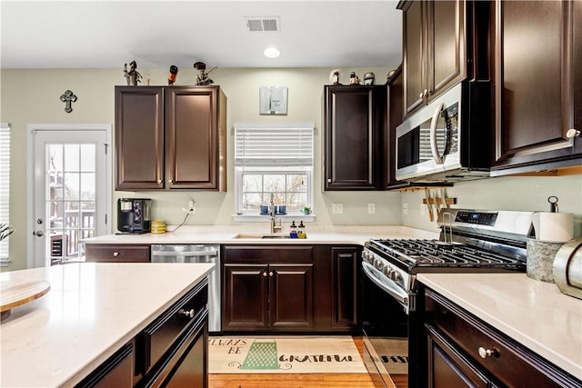 kitchen with dark brown cabinetry, stainless steel appliances, and sink