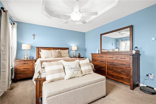 bedroom with a tray ceiling, light colored carpet, and ceiling fan