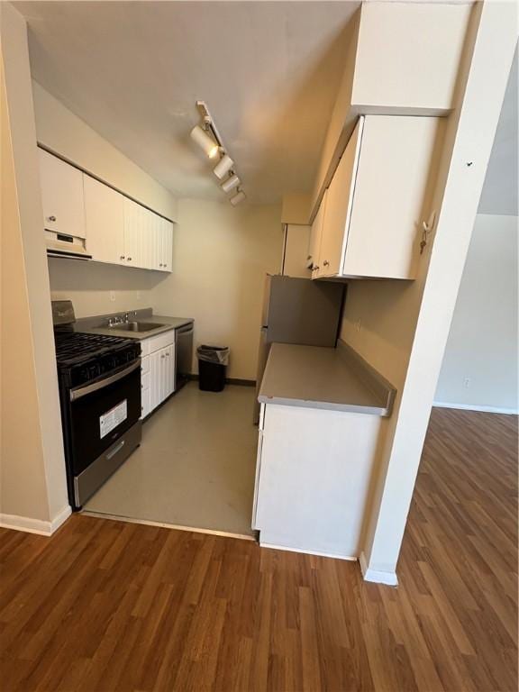 kitchen with sink, stainless steel appliances, track lighting, white cabinets, and dark hardwood / wood-style flooring