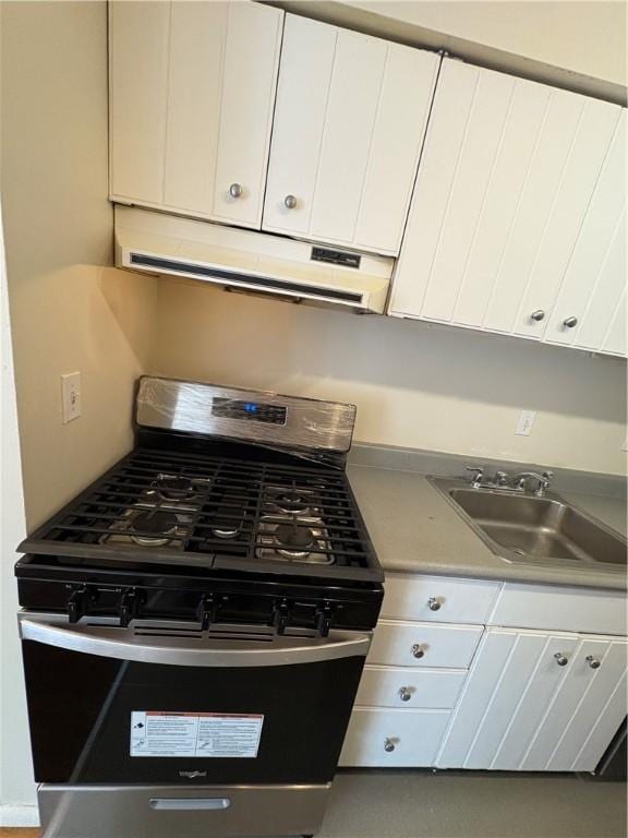 kitchen with stainless steel gas stove, sink, and white cabinetry