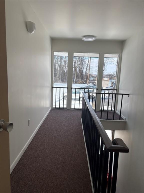 hall featuring dark colored carpet and plenty of natural light