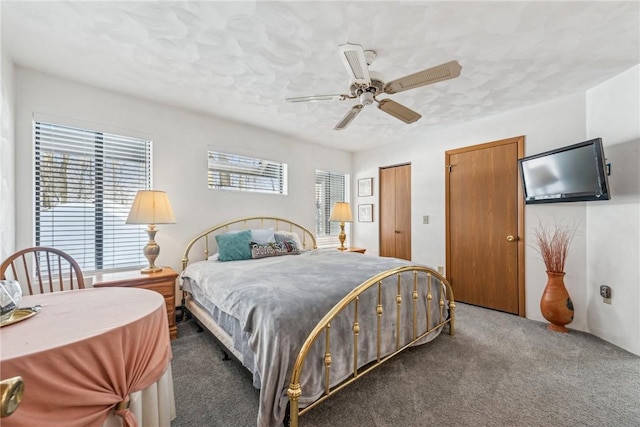 bedroom featuring ceiling fan, dark carpet, and multiple windows