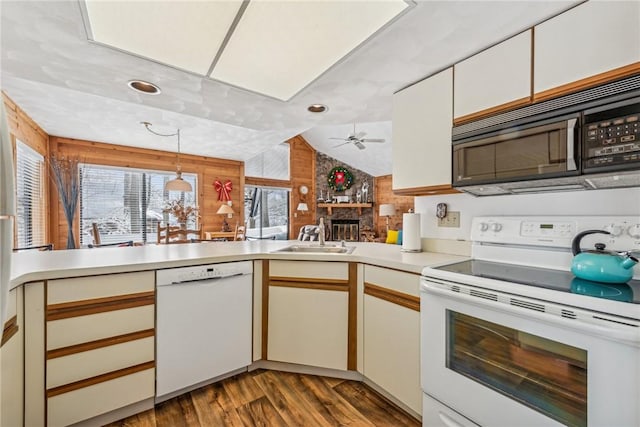 kitchen featuring sink, white appliances, dark wood-type flooring, a fireplace, and vaulted ceiling