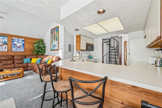 kitchen featuring wood walls, white cabinets, kitchen peninsula, light carpet, and white appliances