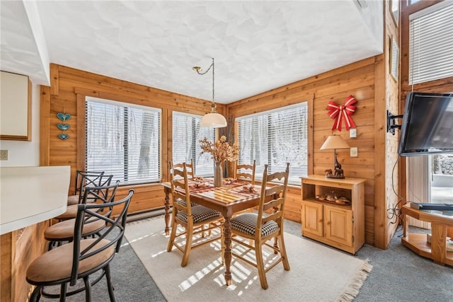 dining room with light carpet, plenty of natural light, and wood walls