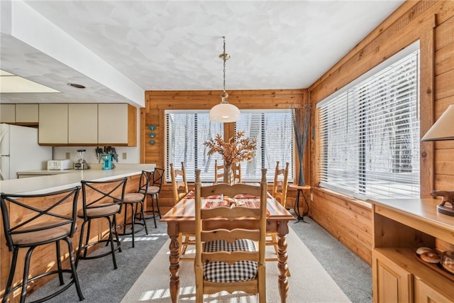 dining area featuring light colored carpet and wood walls