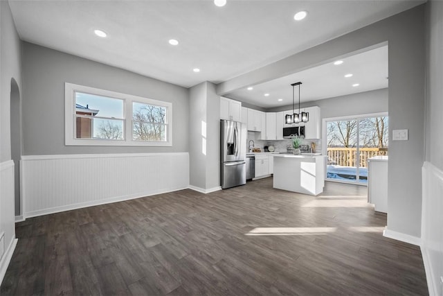 kitchen featuring white cabinetry, dark hardwood / wood-style flooring, a kitchen island, pendant lighting, and stainless steel appliances