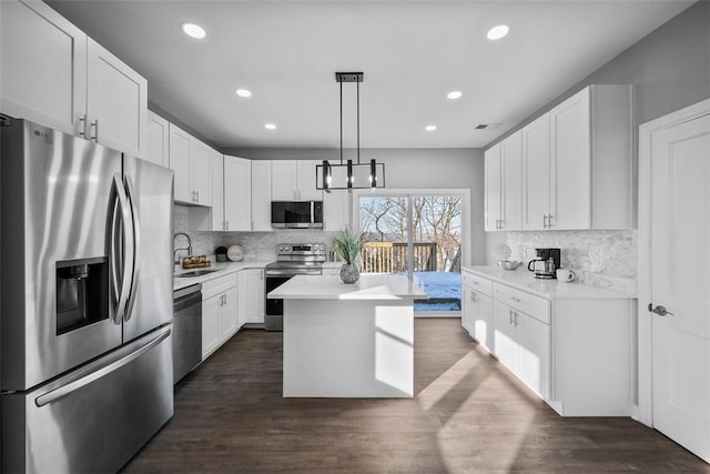 kitchen with sink, a center island, hanging light fixtures, stainless steel appliances, and white cabinets