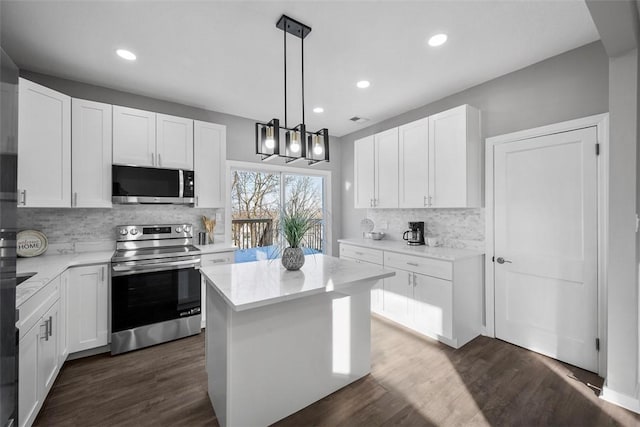 kitchen with a kitchen island, appliances with stainless steel finishes, dark hardwood / wood-style floors, pendant lighting, and white cabinetry