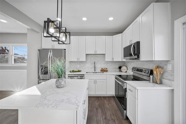 kitchen with sink, decorative light fixtures, appliances with stainless steel finishes, a kitchen island, and white cabinets