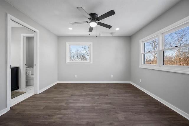 unfurnished bedroom with multiple windows, dark hardwood / wood-style floors, ceiling fan, and ensuite bath