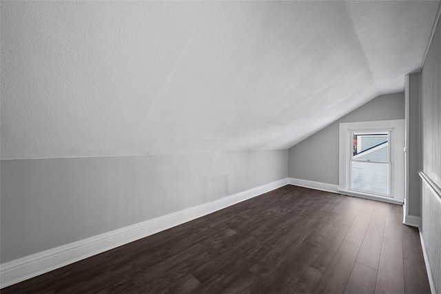 additional living space featuring lofted ceiling, dark hardwood / wood-style floors, and a textured ceiling