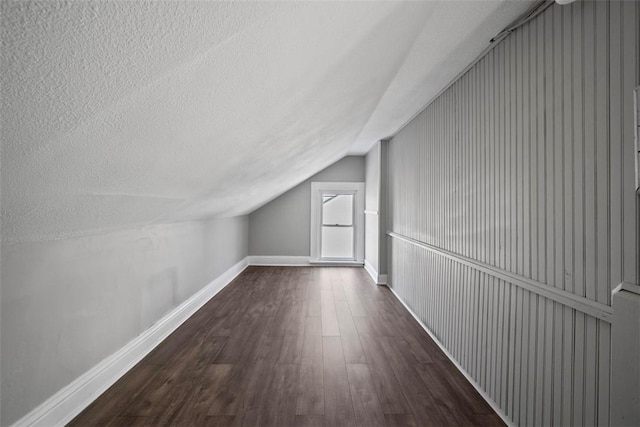 bonus room featuring lofted ceiling, a textured ceiling, and dark hardwood / wood-style flooring