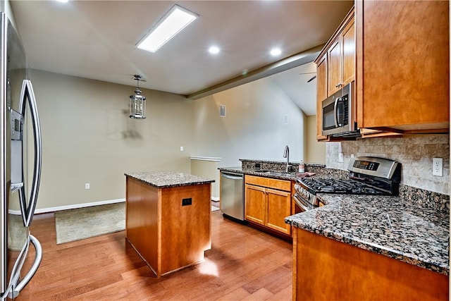 kitchen with a kitchen island, appliances with stainless steel finishes, tasteful backsplash, sink, and dark stone counters