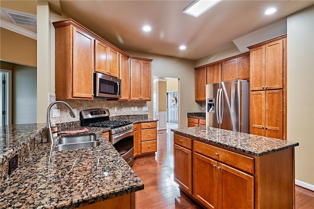 kitchen featuring dark stone countertops, sink, stainless steel appliances, and light hardwood / wood-style floors